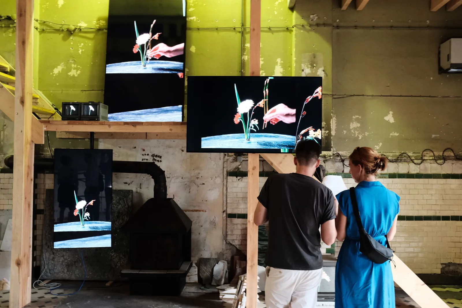 Neue Erinnerungen, Eröffnung: Besucher betrachten Videobildschirme mit Tanzszenen in einer Industriehalle