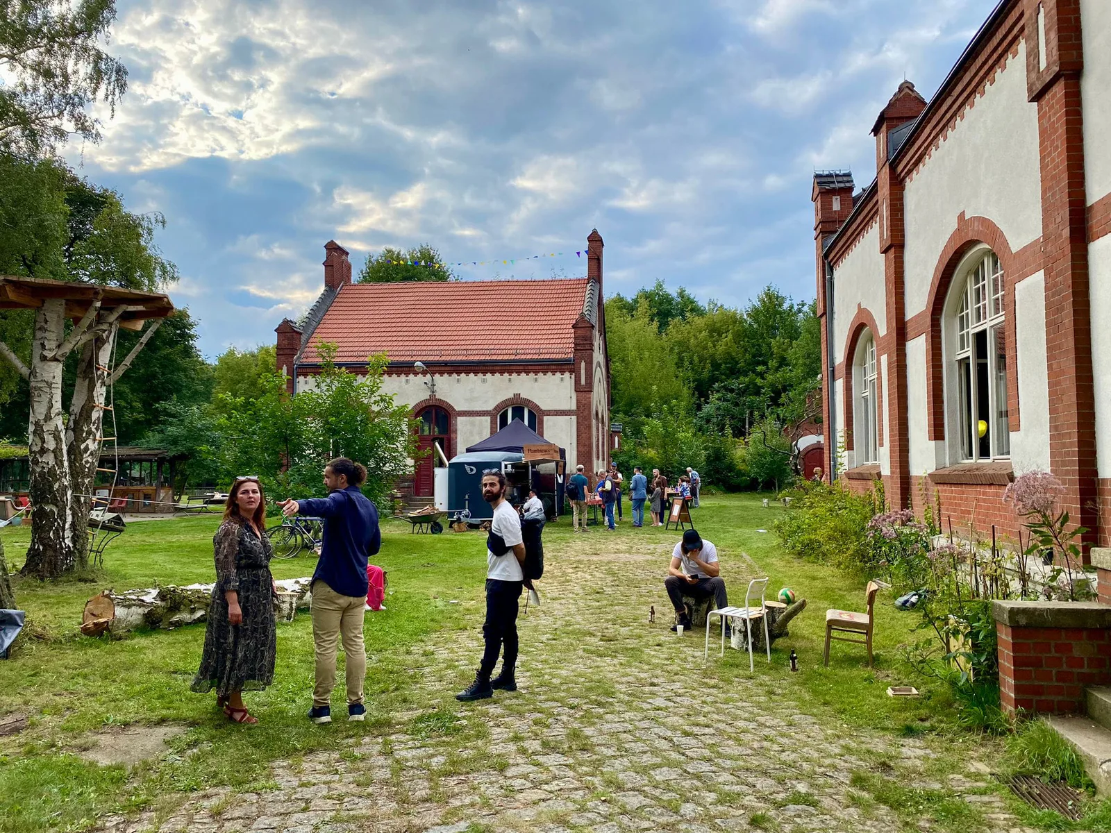 Neue Erinnerungen, Eröffnung: Besucher im Garten vor den Backsteingebäuden der Gerichtshöfe