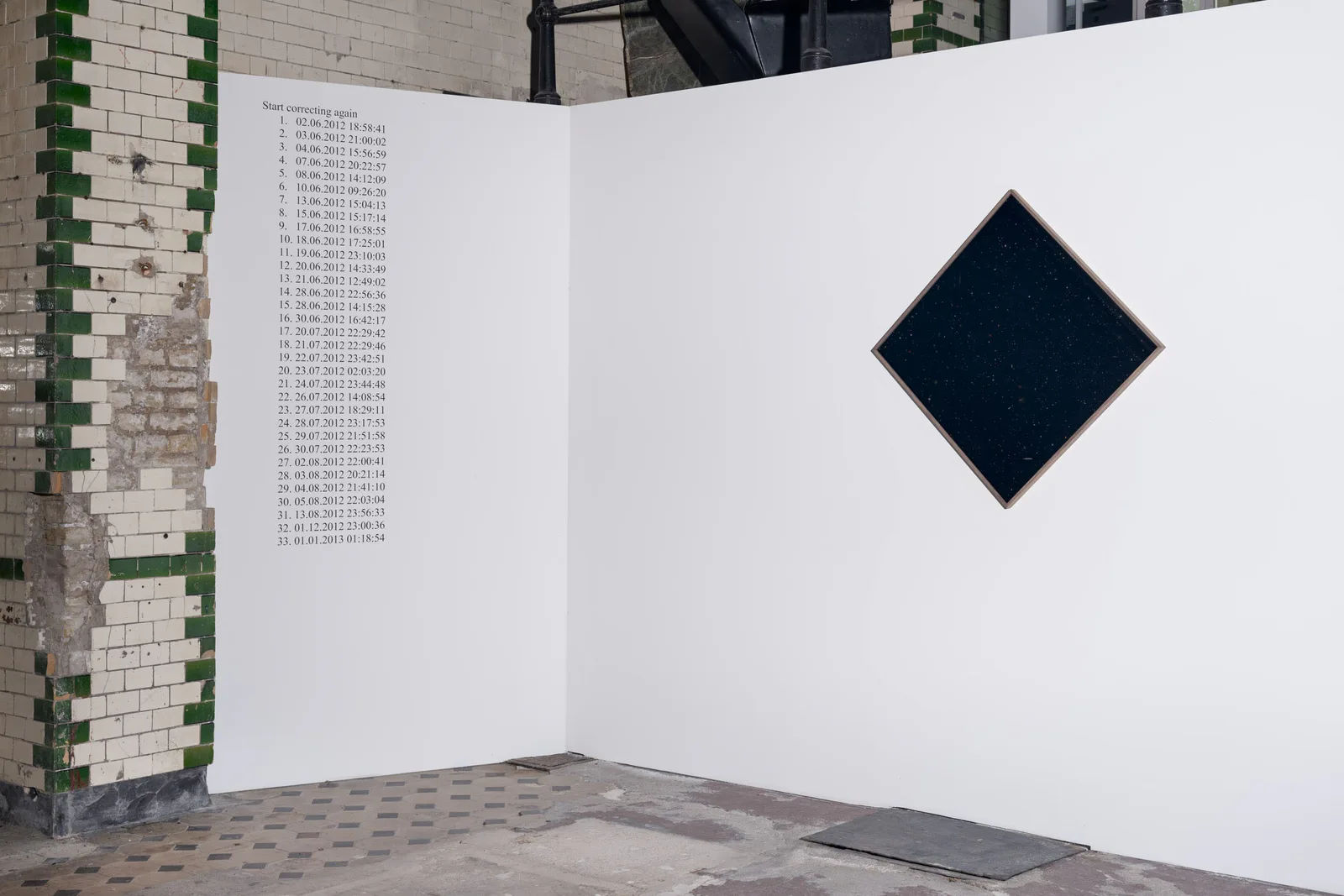 Neue Erinnerungen: weiße Stellwand mit einem schwarzen Quadrat, auf die Spitze gestellt, neben einer Kachelwand