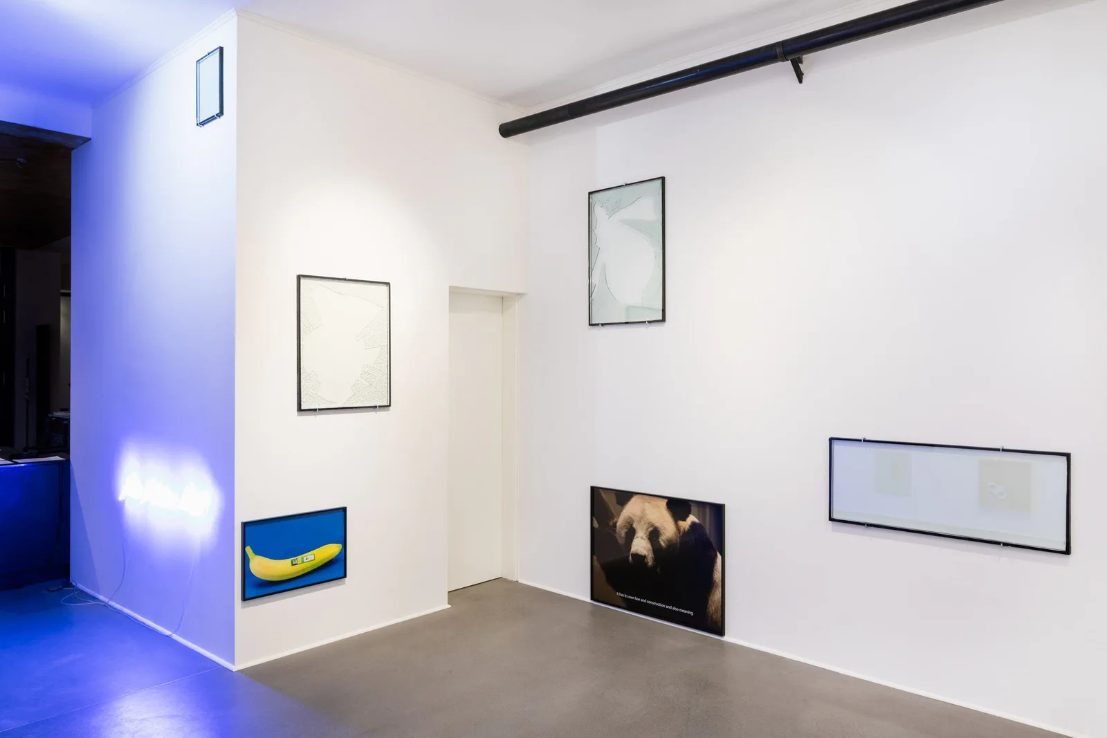 Everything about the contemporary is panda, installation view: gallery room with empty frames, panda pictures, a banana picture and blue light