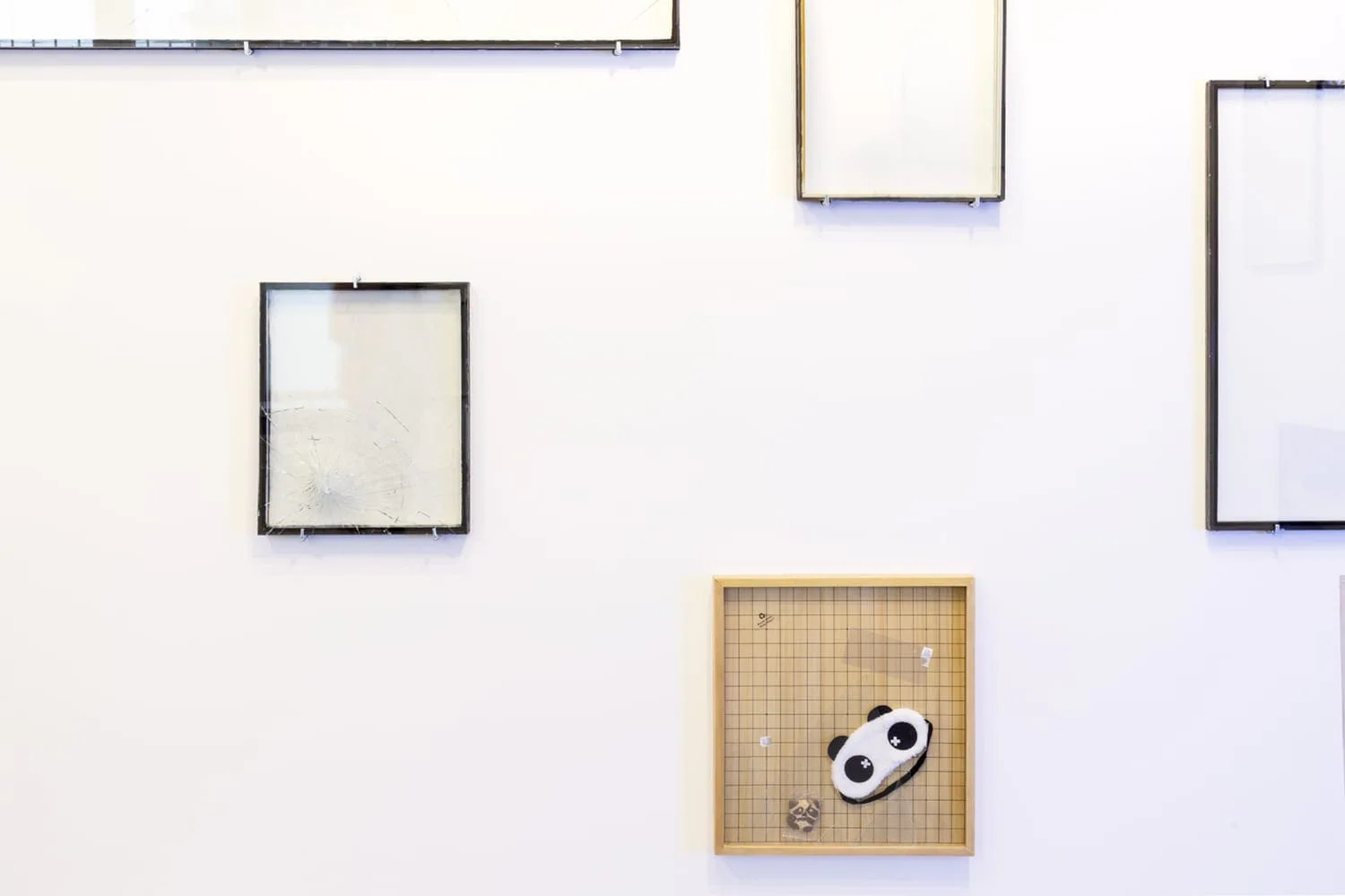 The incredulity of Saint Thomas II, Installationsansicht: leere Glasrahmen an einer Wand, darunter ein Go-Brett mit Panda-Figur
