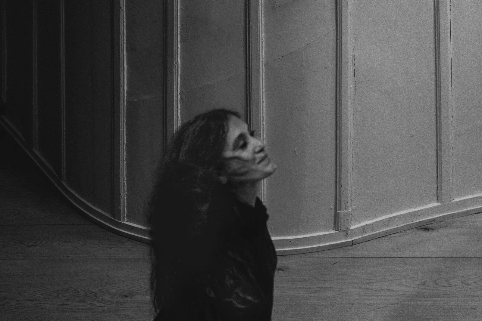Black-and-white picture: Elshan Ghasimi with her face raised in front of the theatre's wood panelling