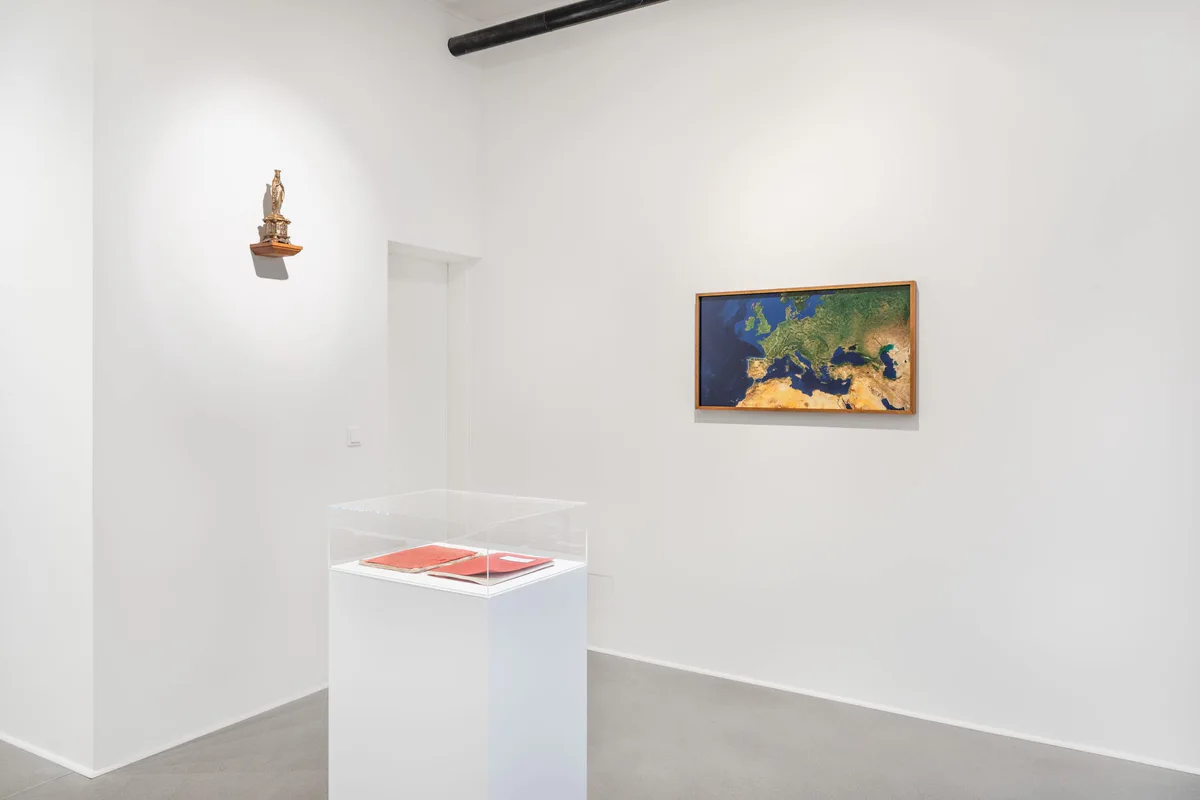 Marianische Antiphonen I, exhibition view: a room with a small figure on the wall, a landscape painting and a display case