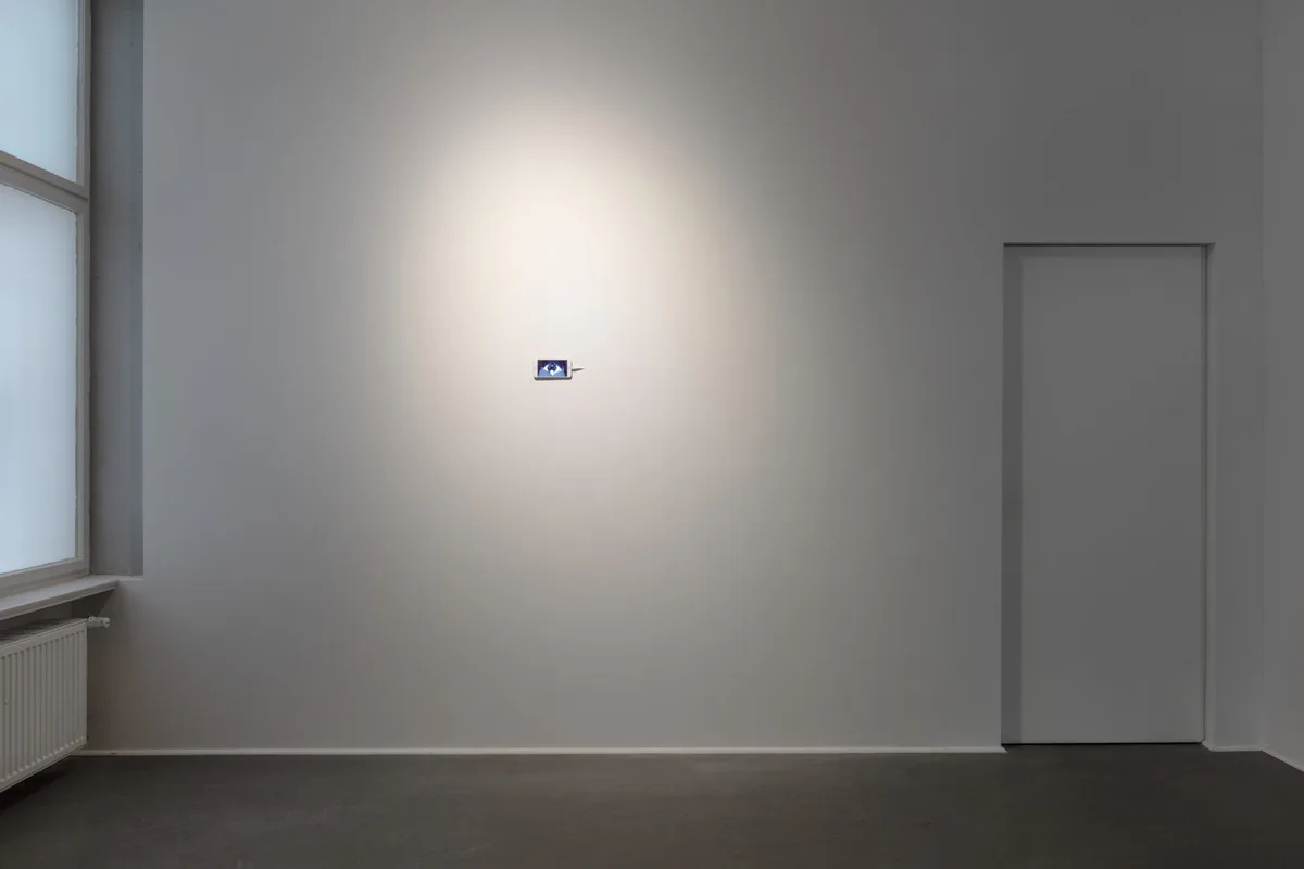Installationsansicht: ein kleines Smartphone allein an einer großen weißen Wand