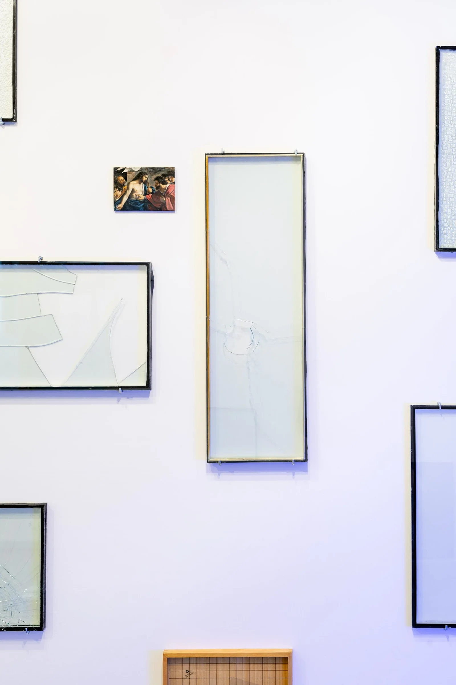 Installation view: empty glass frames of various sizes and a small picture on a wall