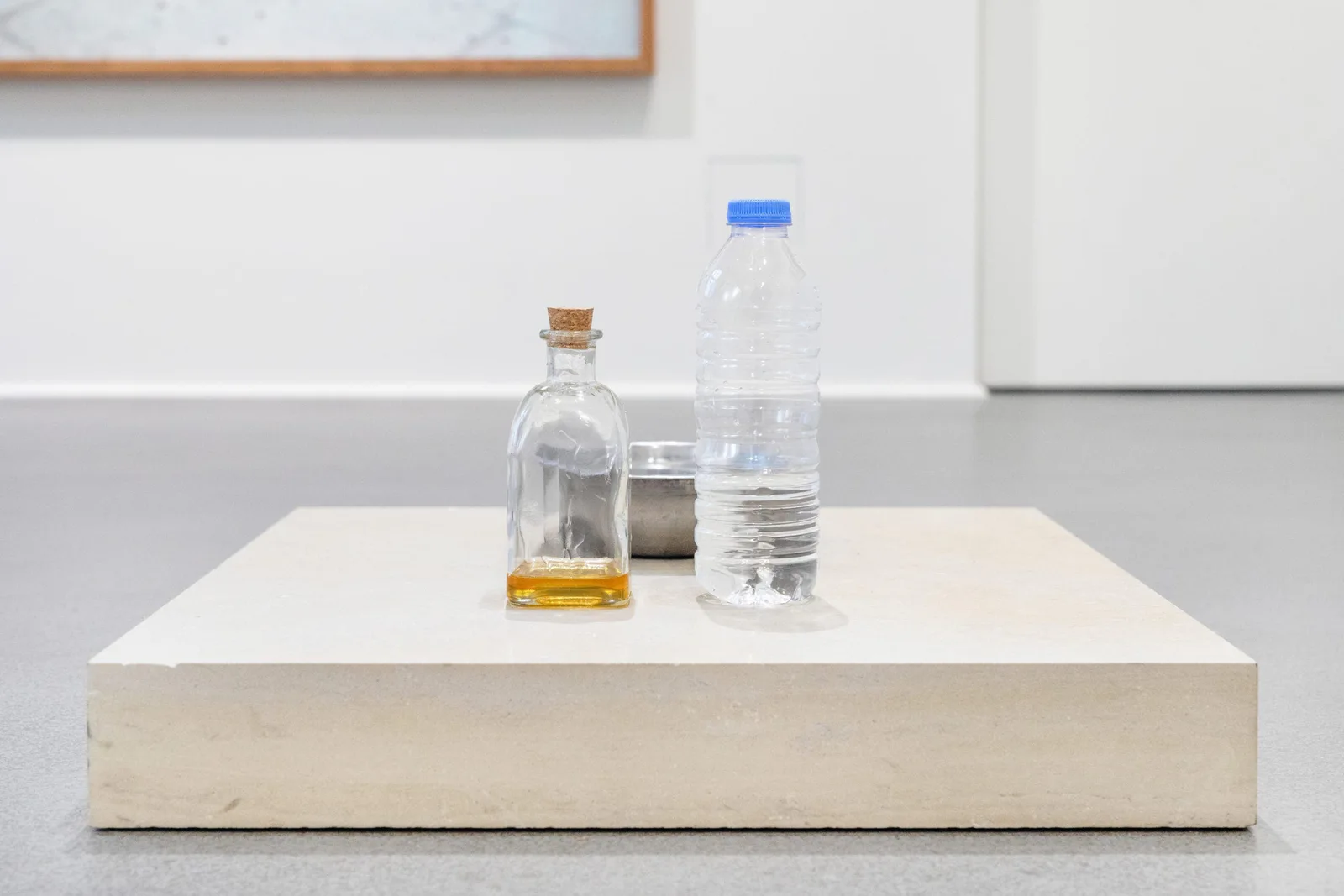 GABRIEL – Urraum Altar & Die Dritte Waschung oder die Honigtaufe (Werkzeuge), 2017–2019: a bottle of honey and a water bottle on a flat white plinth