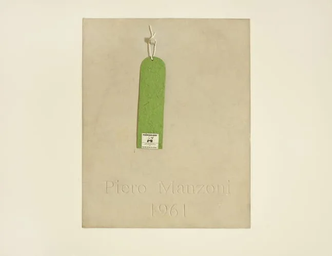Framed pale sheet with a green tag and the inscription “Piero Manzoni 1961”