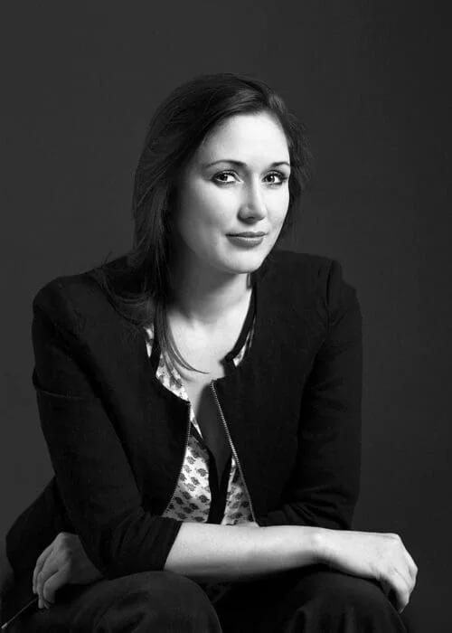 Portrait of Eleonora Frolov, seated against a dark background, black and white