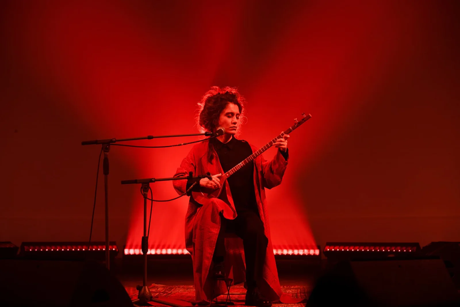 Elshan Ghasimi spielt Tar auf einer rot beleuchteten Bühne, Foto Simona Bortolotti