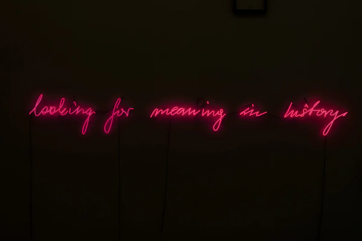 Michal Martychowiec, looking for meaning in history, 2017: rote Neonschrift „looking for meaning in history“ in einem dunklen Raum