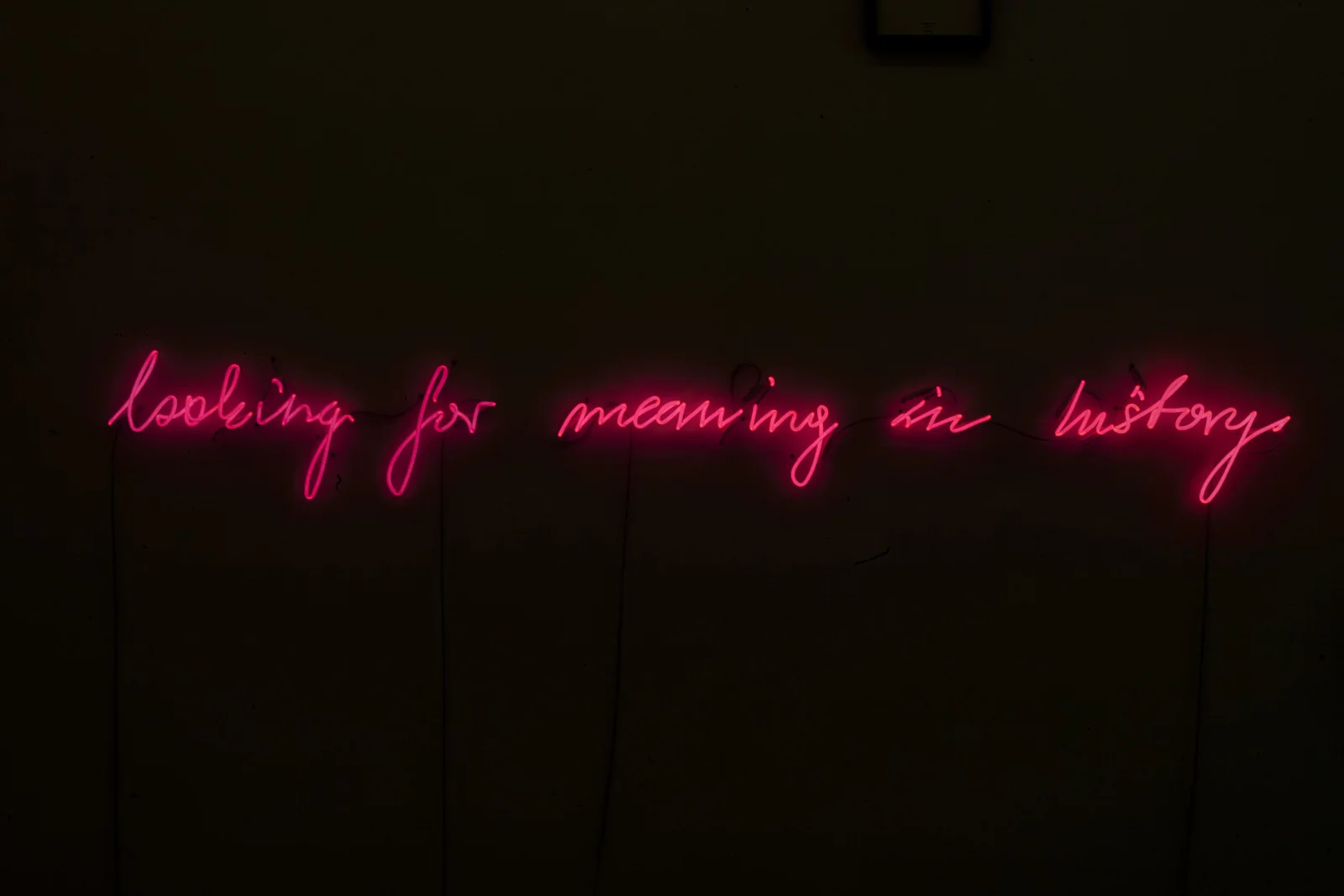 Michal Martychowiec, looking for meaning in history, 2017: rote Neonschrift „looking for meaning in history“ in einem dunklen Raum