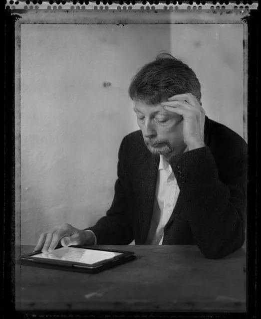 Porträt von Reinhard Knodt an einem Tisch mit einem Blatt Papier, Schwarz-Weiß mit altem Fotorand