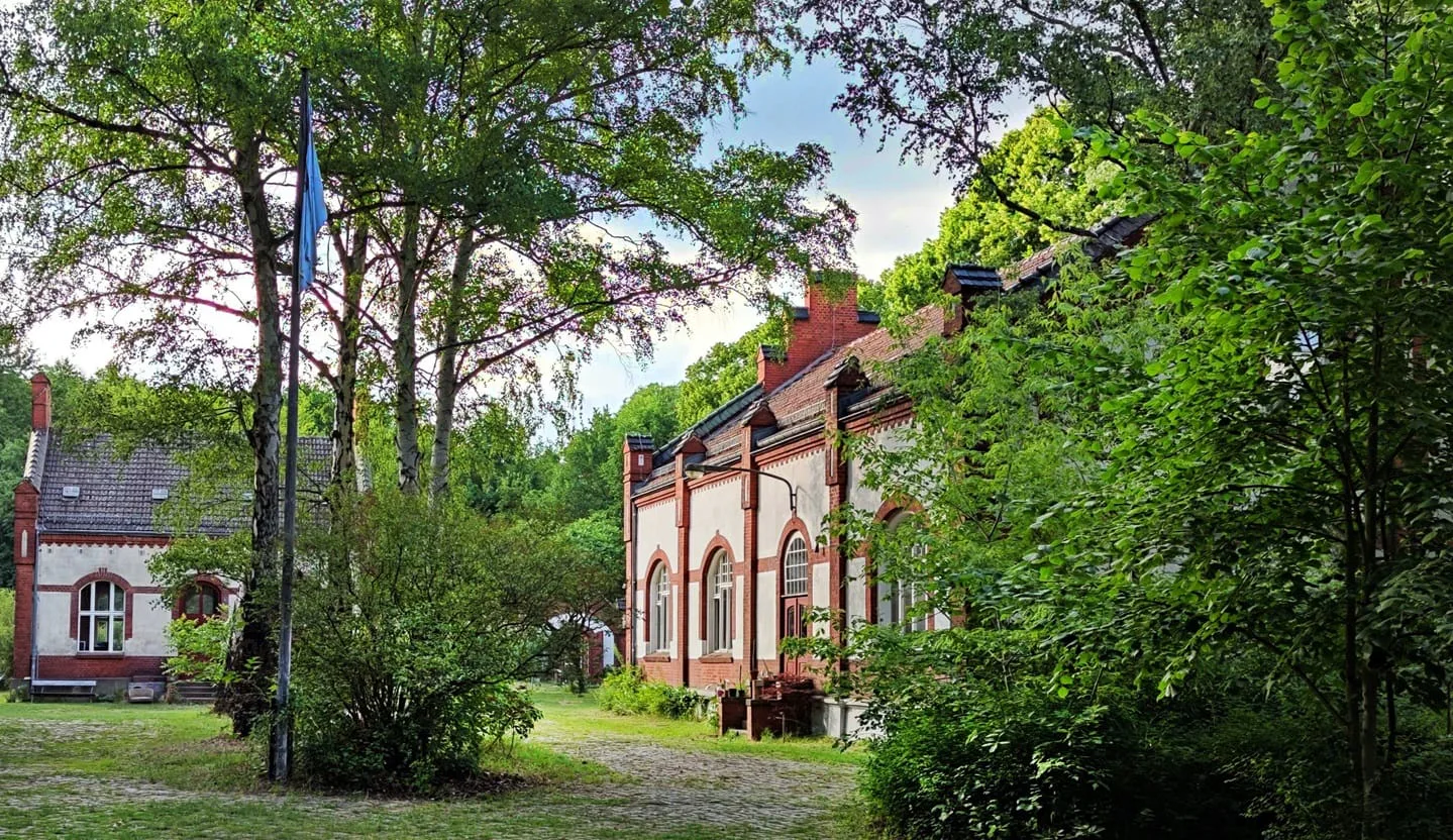 Das alte Pumpwerk im Privatpark: Backsteingebäude zwischen Bäumen mit einem Fahnenmast