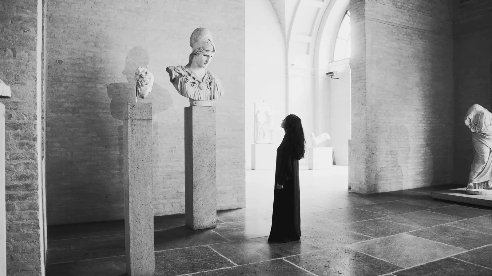 Pallas Athena, Patronin von Elshan Ghasimis Radif-Erneuerung: Elshan Ghasimi in Schwarz vor einer antiken Büste in einem Museumssaal, Schwarz-Weiß