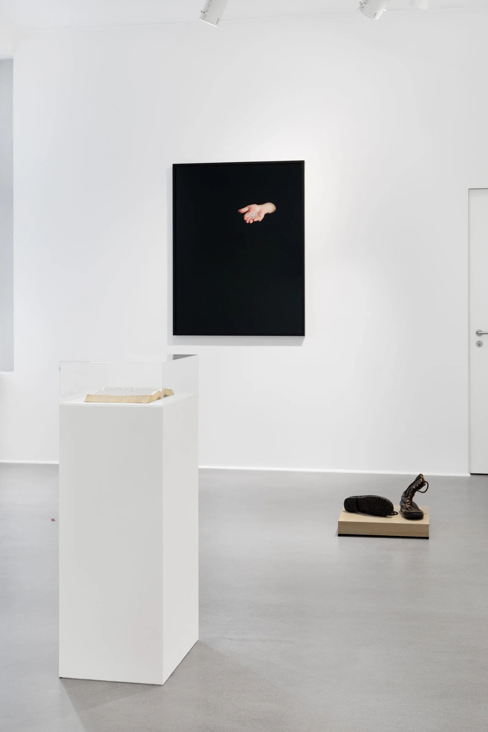 What remains the poets provide, installation view: black picture with an open hand, a plinth and an object on the floor