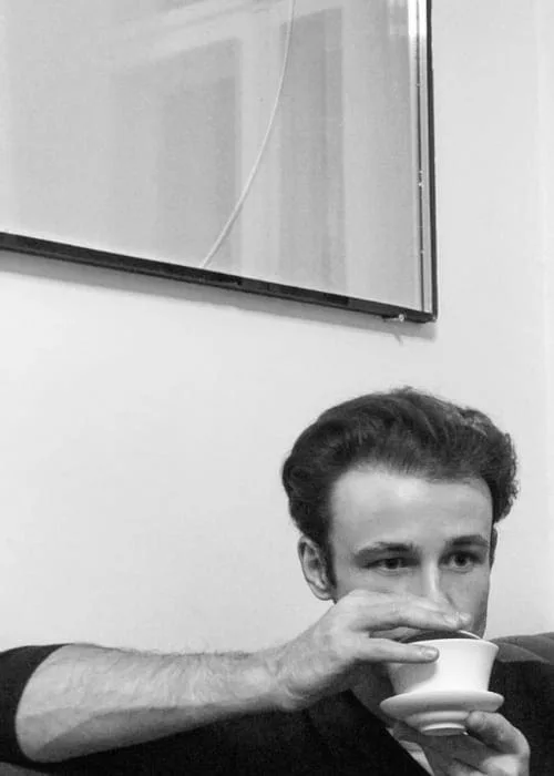 Portrait of Michal Martychowiec drinking from a cup, black and white