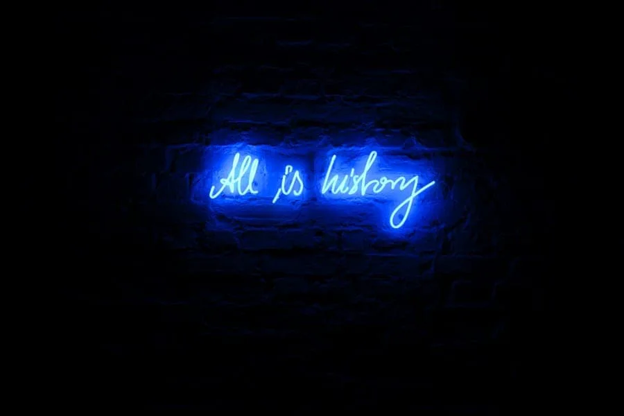 Michal Martychowiec – All is history: blaue Neonschrift „All is history“ an einer dunklen Wand