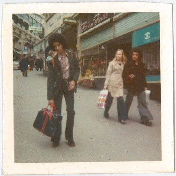 El Arbi Bouqdib mit Reisetasche auf einer Einkaufsstraße, Passanten im Hintergrund, altes Farbfoto