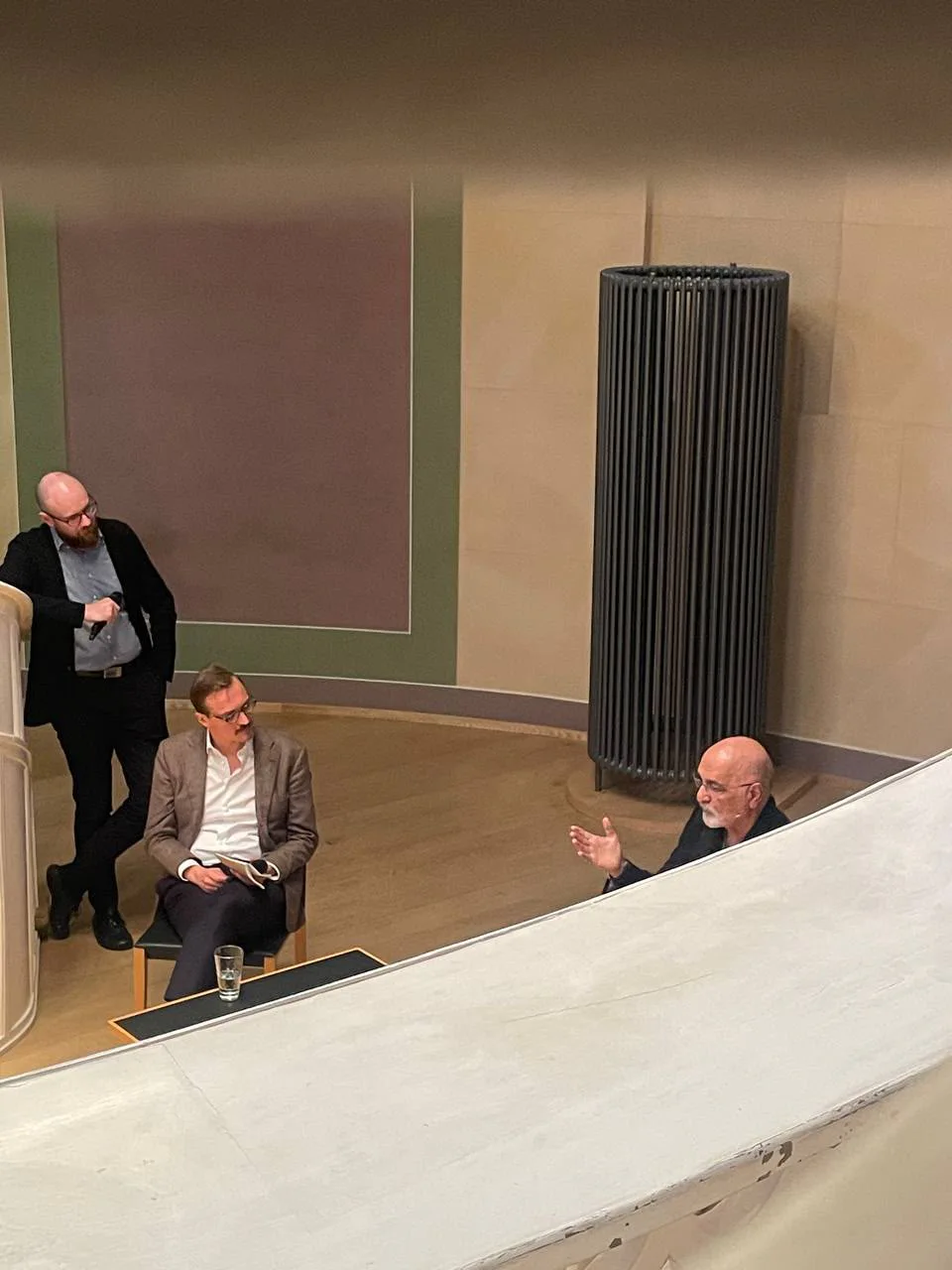 Gespräch im Tieranatomischen Theater von oben gesehen: zwei Männer sitzen, ein dritter steht daneben
