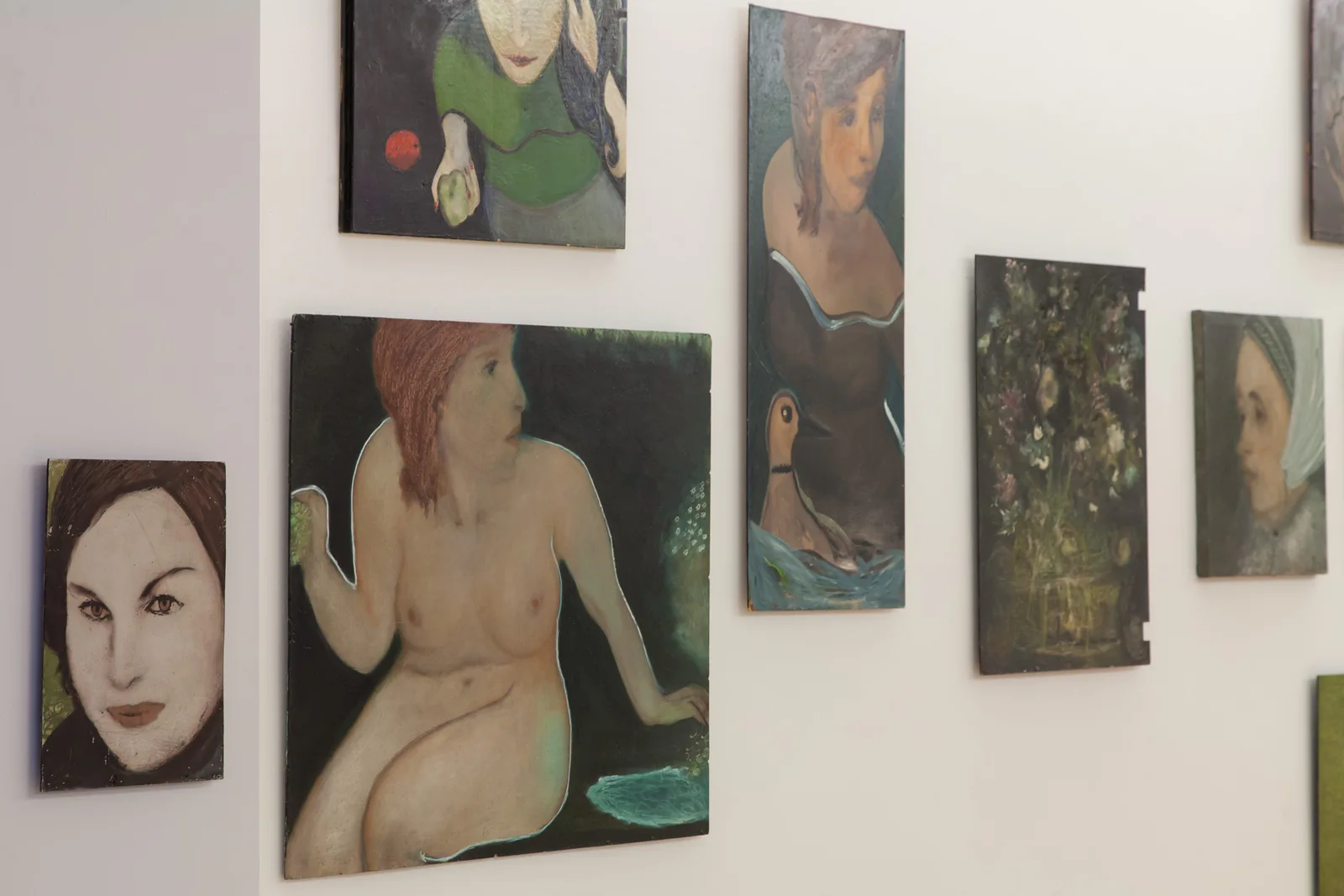 Installation view: paintings by Hilarion Manero with women's faces and nudes on a white wall