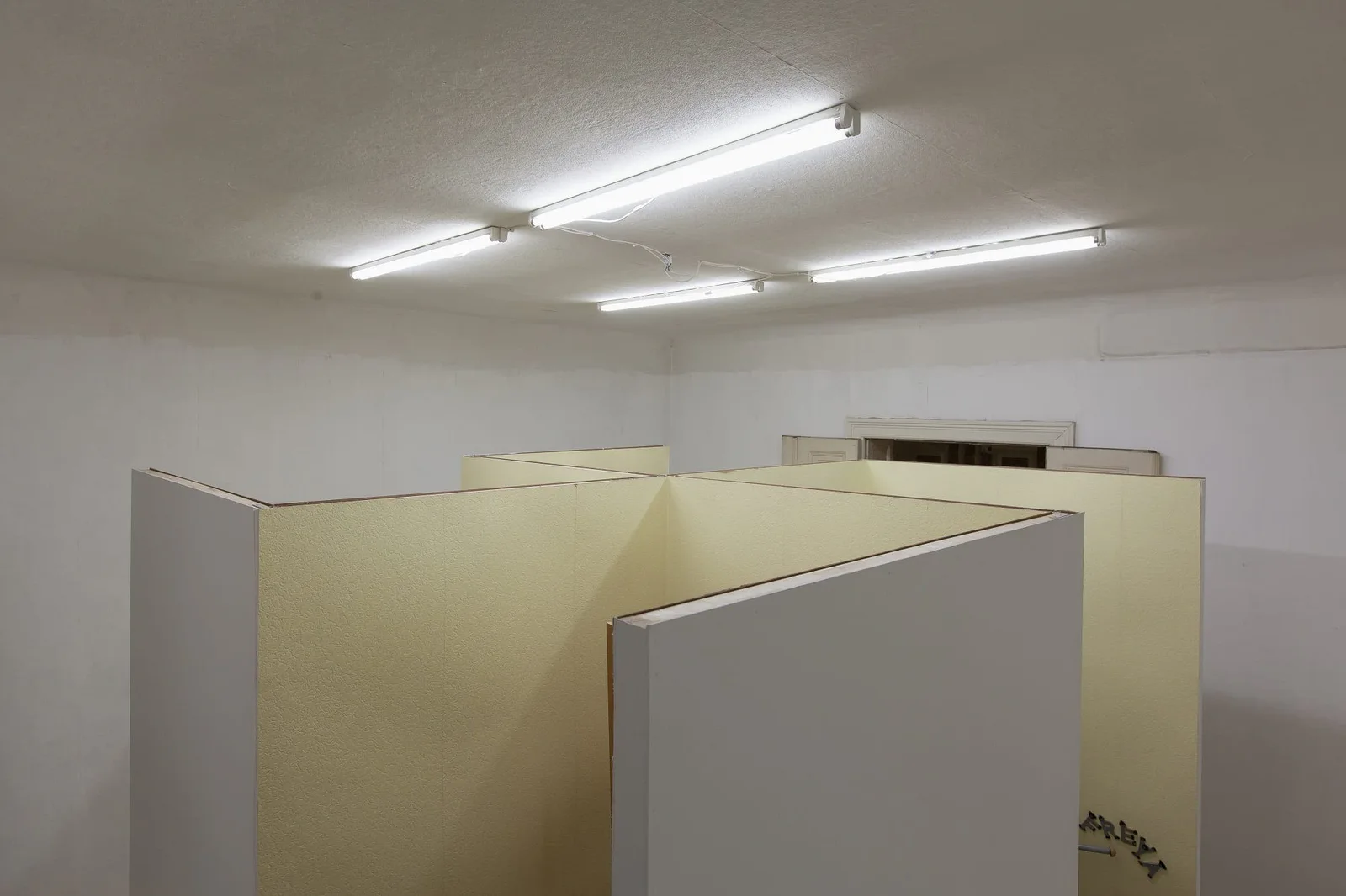Henrike Naumann, Unbetitelt, 2013: weiße Stellwände in einem Raum mit Neonröhren