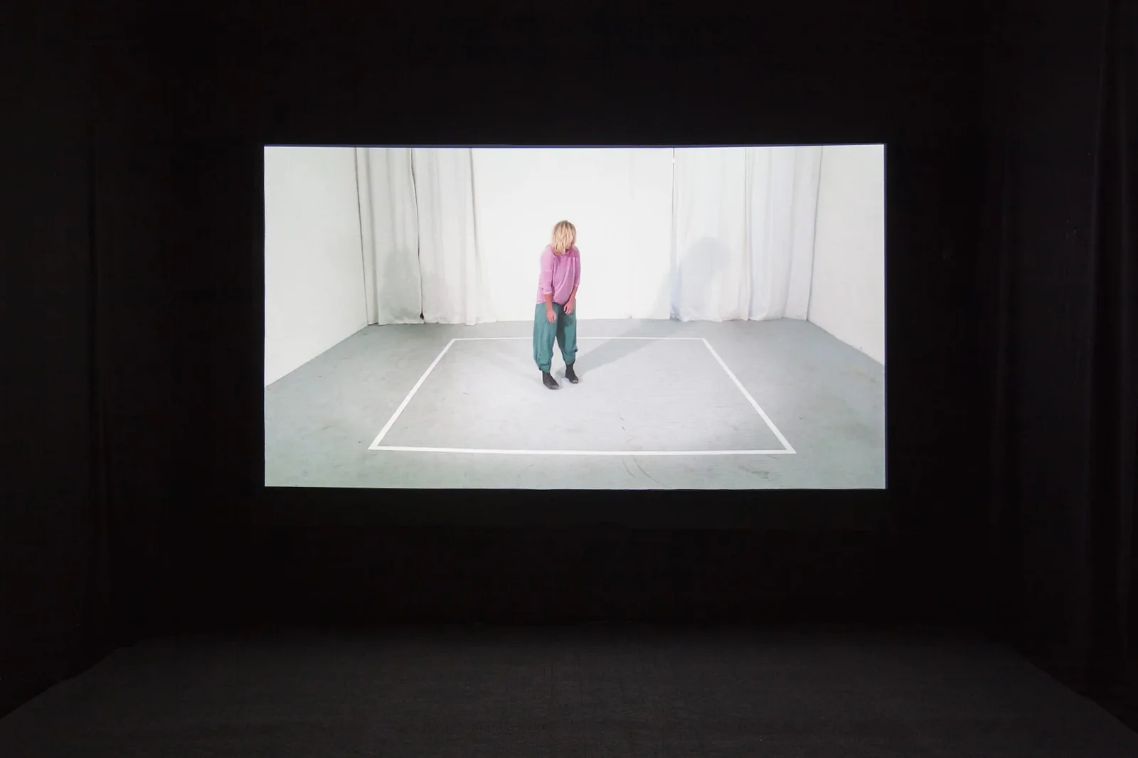 Marcel Tarelkin, Figure 2, 3, 4, 7, 12, 2013 (Video): Projektion einer Person in rosa Pullover in einem weißen Raum