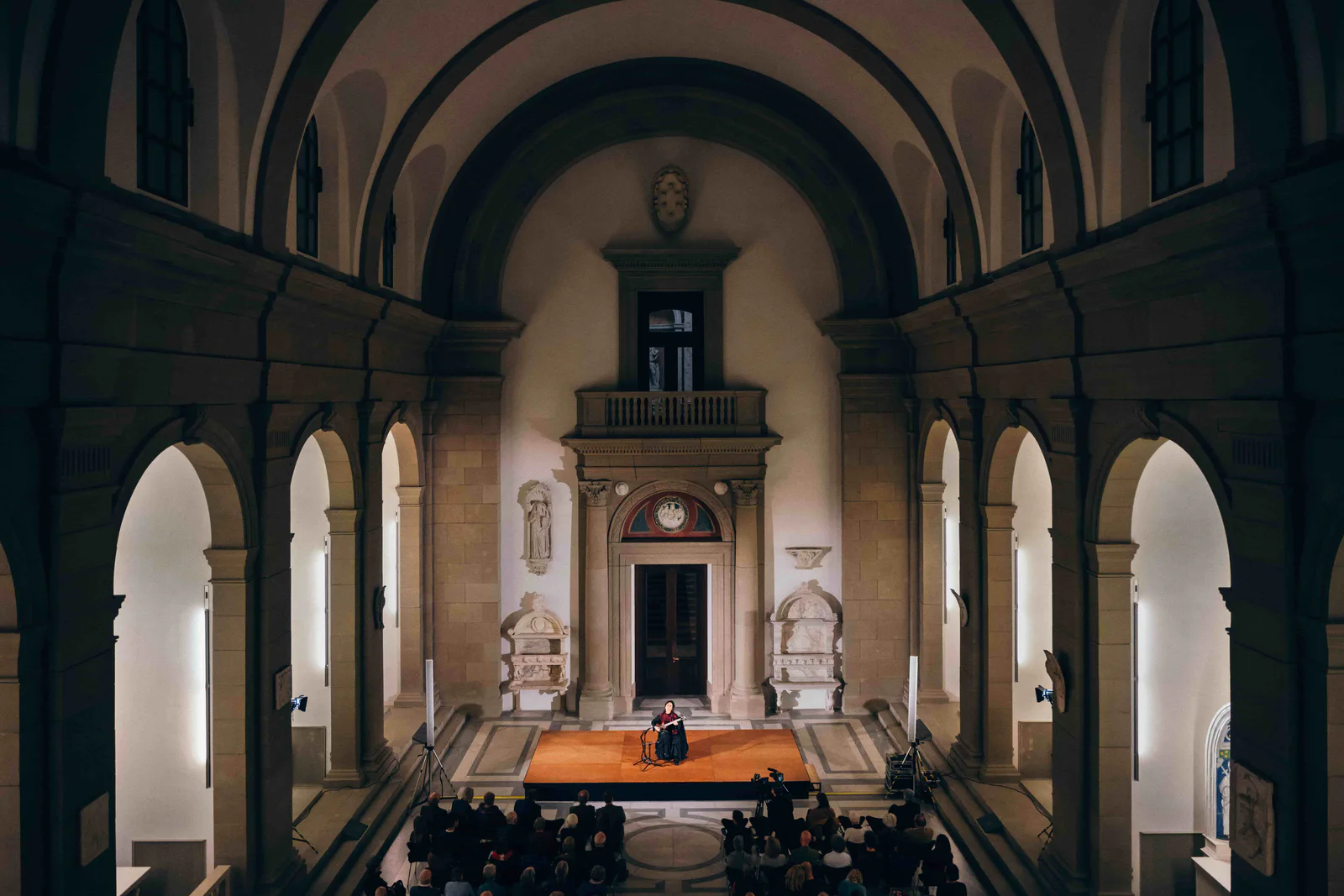 Konzertpublikum in einem Kirchensaal mit Säulen und Kassettendecke