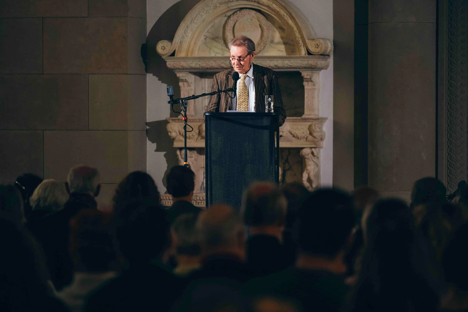 Ein Redner am Pult vor Publikum in einem historischen Saal
