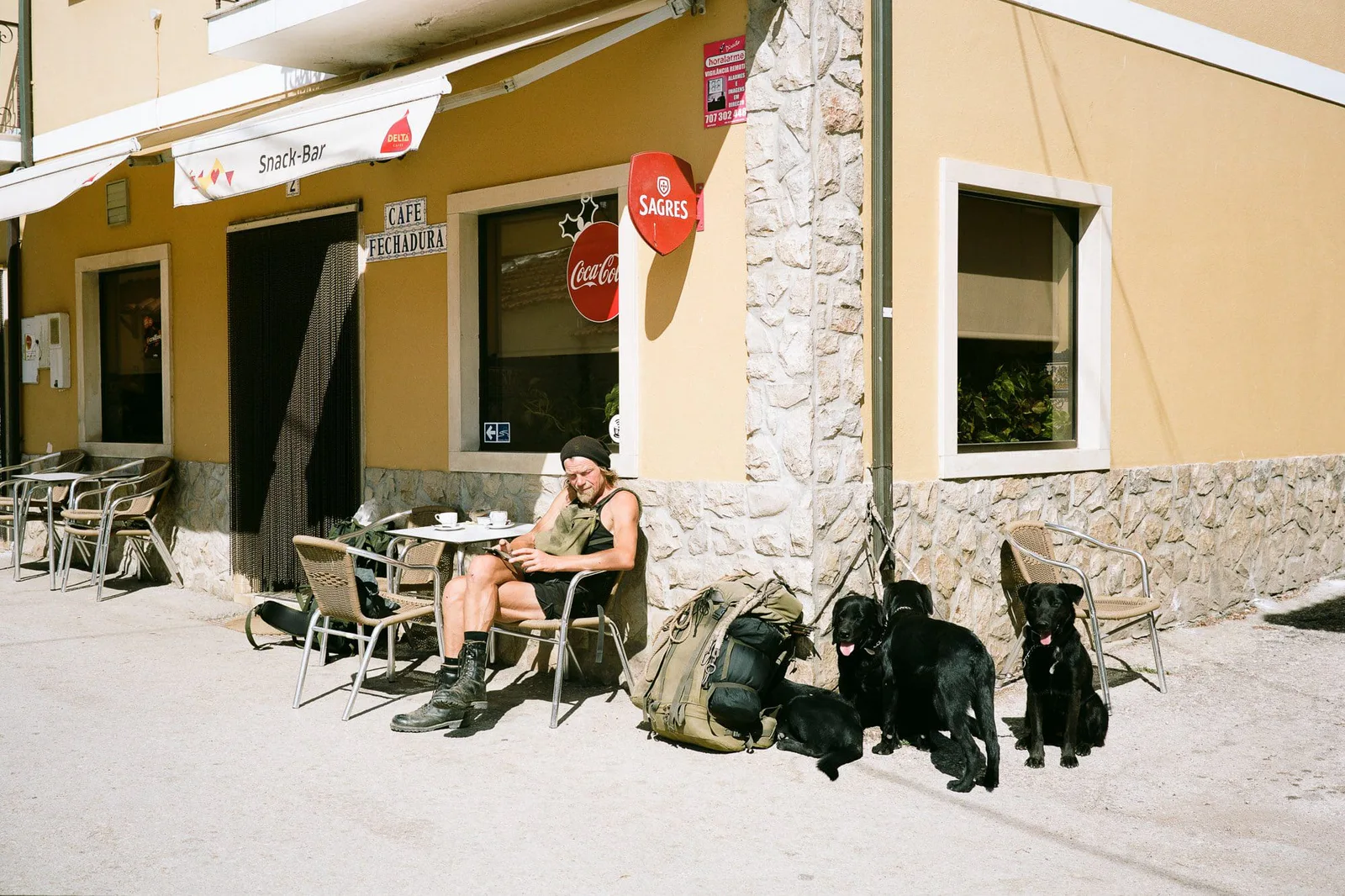 A man sitting with several dogs in front of a café in the sun, photo Stefan Hähnel