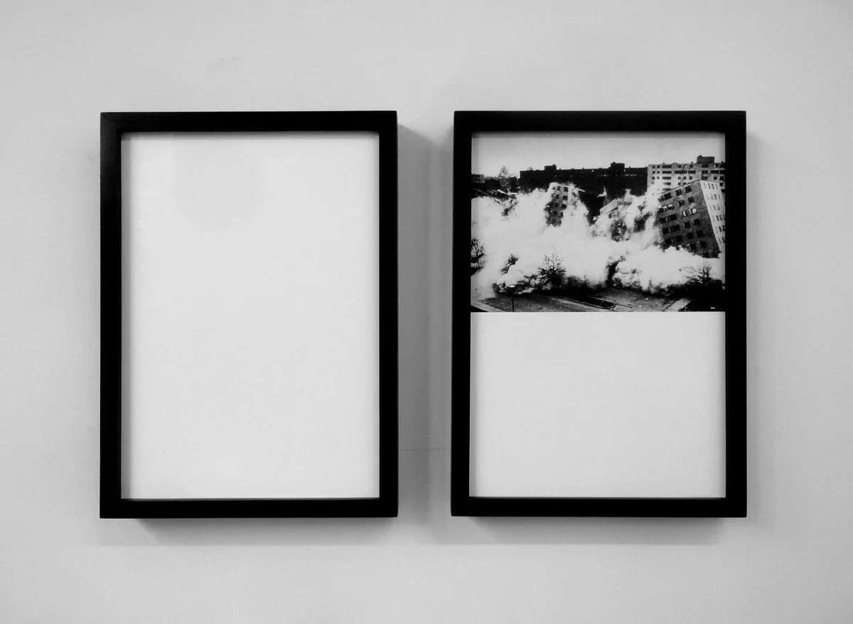 The road leads back and back to the black square: zwei schwarz gerahmte Tafeln an einer weißen Wand, eine leer, eine mit Schwarz-Weiß-Foto einer Baumreihe