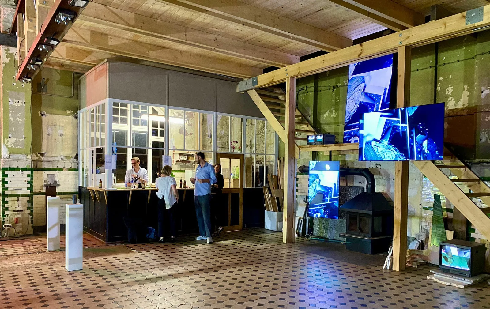 Videoinstallation von Stark & Shakupa: Bildschirme in einem Holzgerüst in einer Halle mit Besuchern